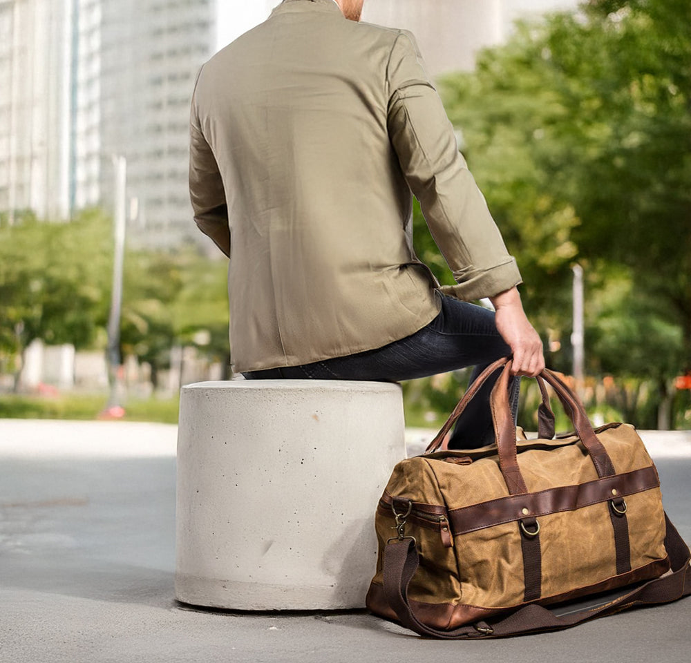 Man sitting on a concrete block with a stylish Mount Shasta men's duffle bag on the ground beside him.