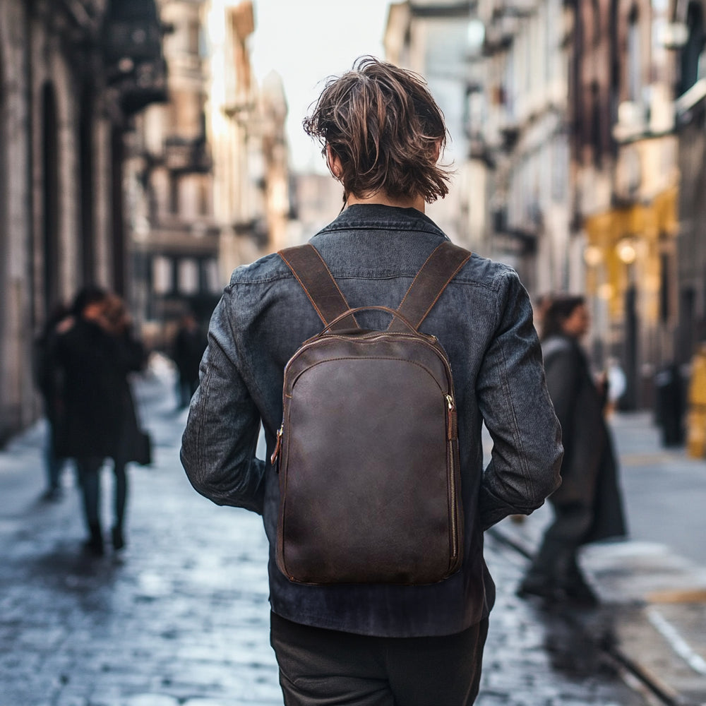 Man walking in a city street wearing a tan leather rucksack, showcasing its stylish and functional design.