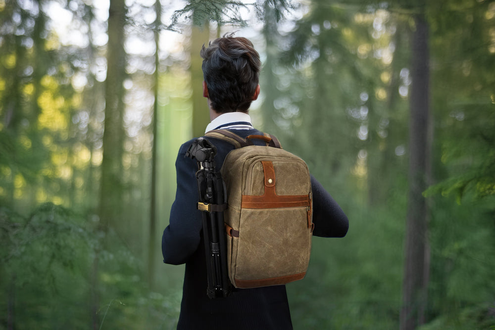 A person walking in a forest with a stylish canvas photography backpack, perfect for adventures and photo outings.