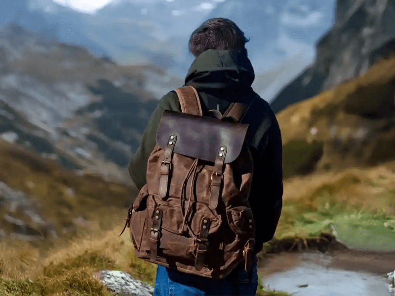 Person with a brown backpack hiking in a scenic mountainous landscape.
