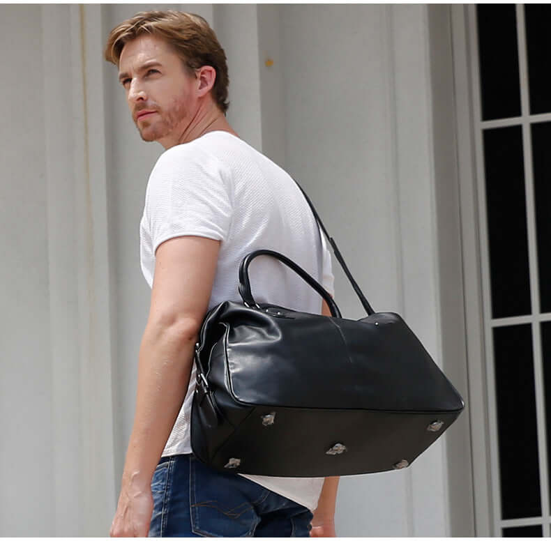 Man carrying a stylish black leather holdall bag, perfect for travel and everyday use.