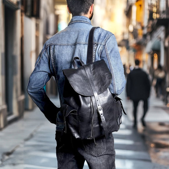Stylish man wearing a small black leather backpack while walking in an urban setting.