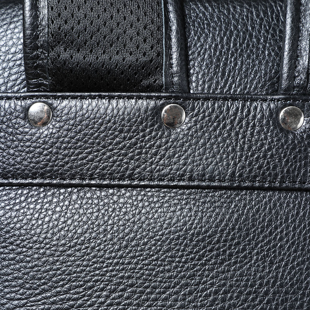 Close-up of the textured surface and metallic studs of a black leather bookbag, showcasing durable design details.