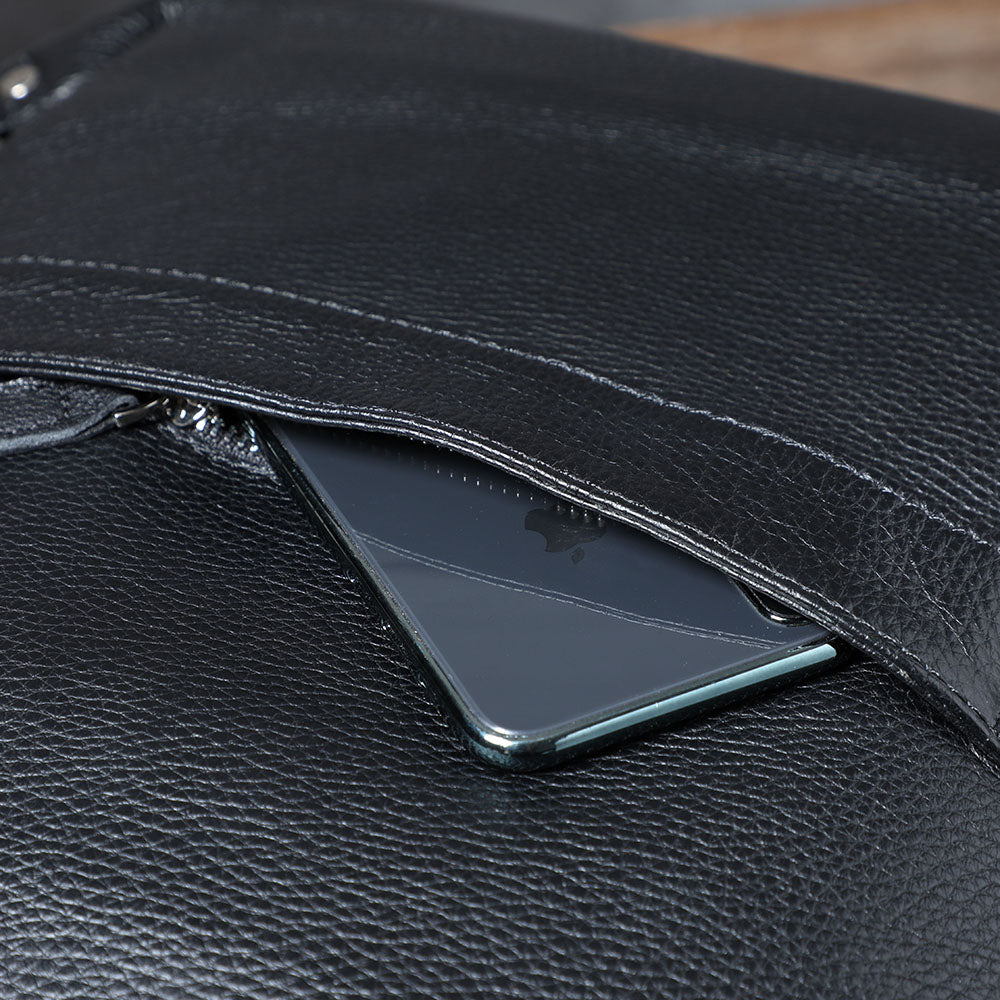 Close-up of a black leather bookbag showcasing a smartphone inside the zippered pocket.