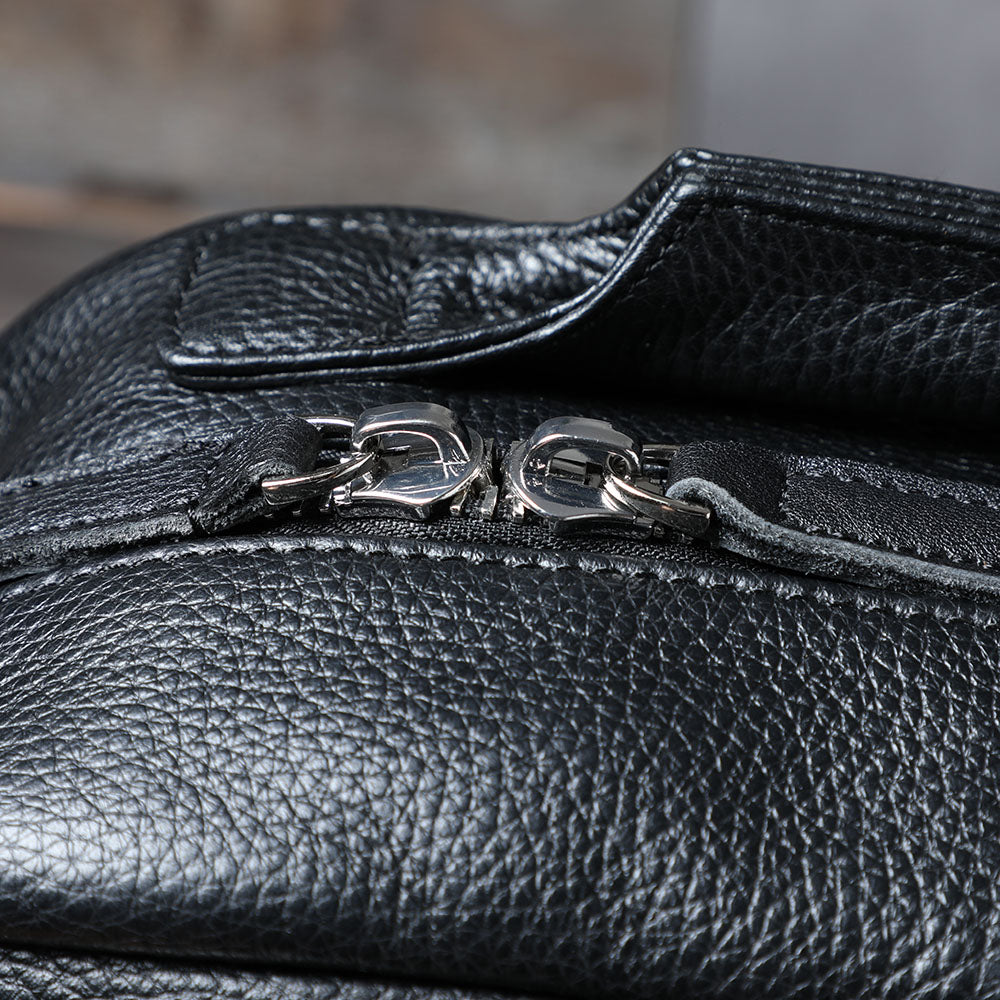 Close-up of black leather bookbag zipper, showcasing durable materials and sleek design for stylish use.