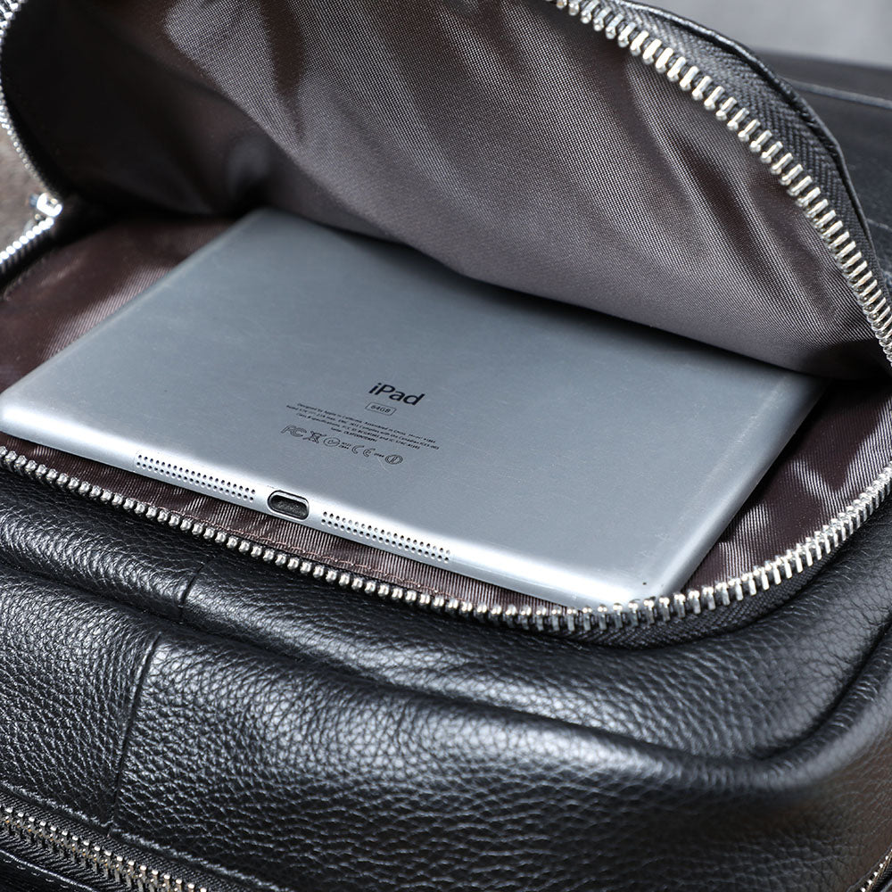 Close-up of a black leather bookbag interior featuring a silver iPad inside.
