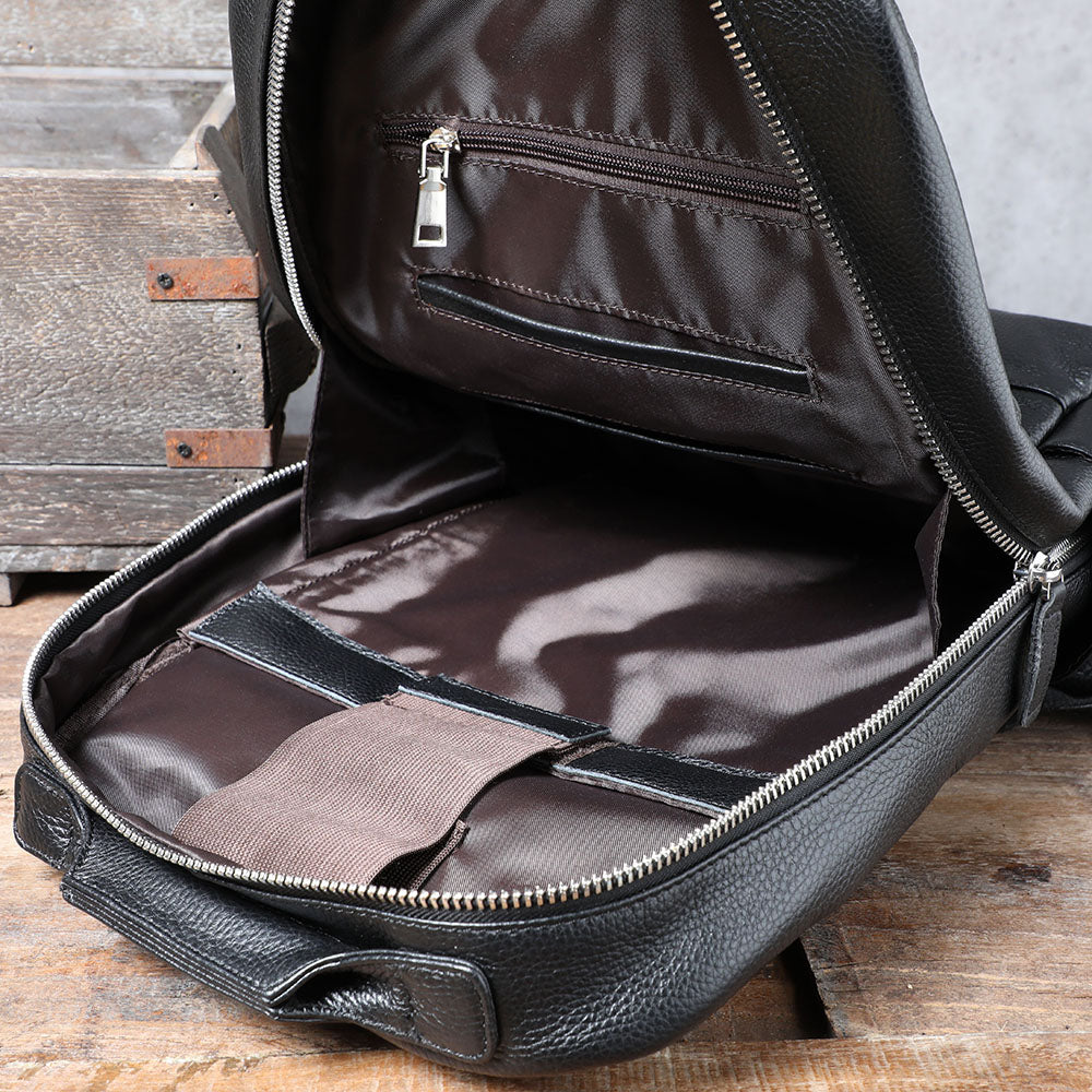 Interior view of a black leather bookbag showing zippered pocket and spacious compartment, perfect for organization.