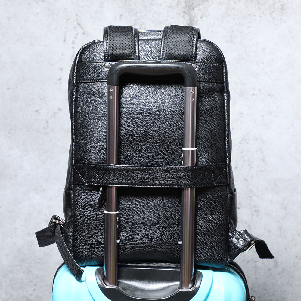 Black leather bookbag with trolley handle on turquoise suitcase, stylish and functional for travel.