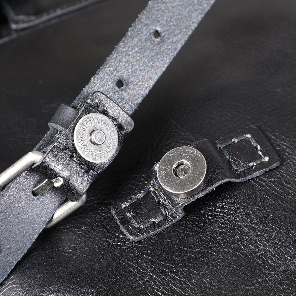 Close-up of the adjustable strap and metal fittings on a small black leather backpack from Lake Victoria.