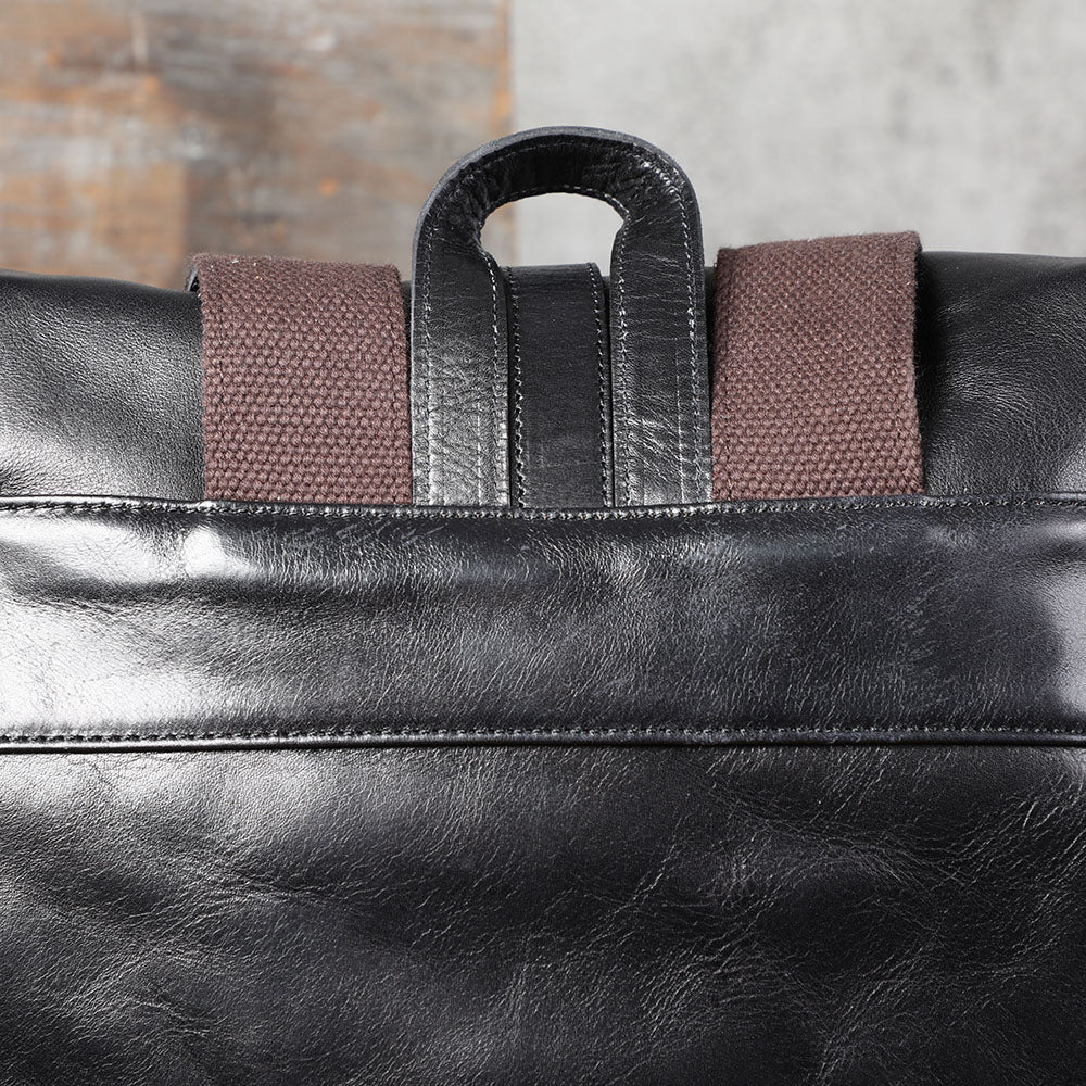 Close-up of the top handle and straps of a small black leather backpack from Lake Victoria.