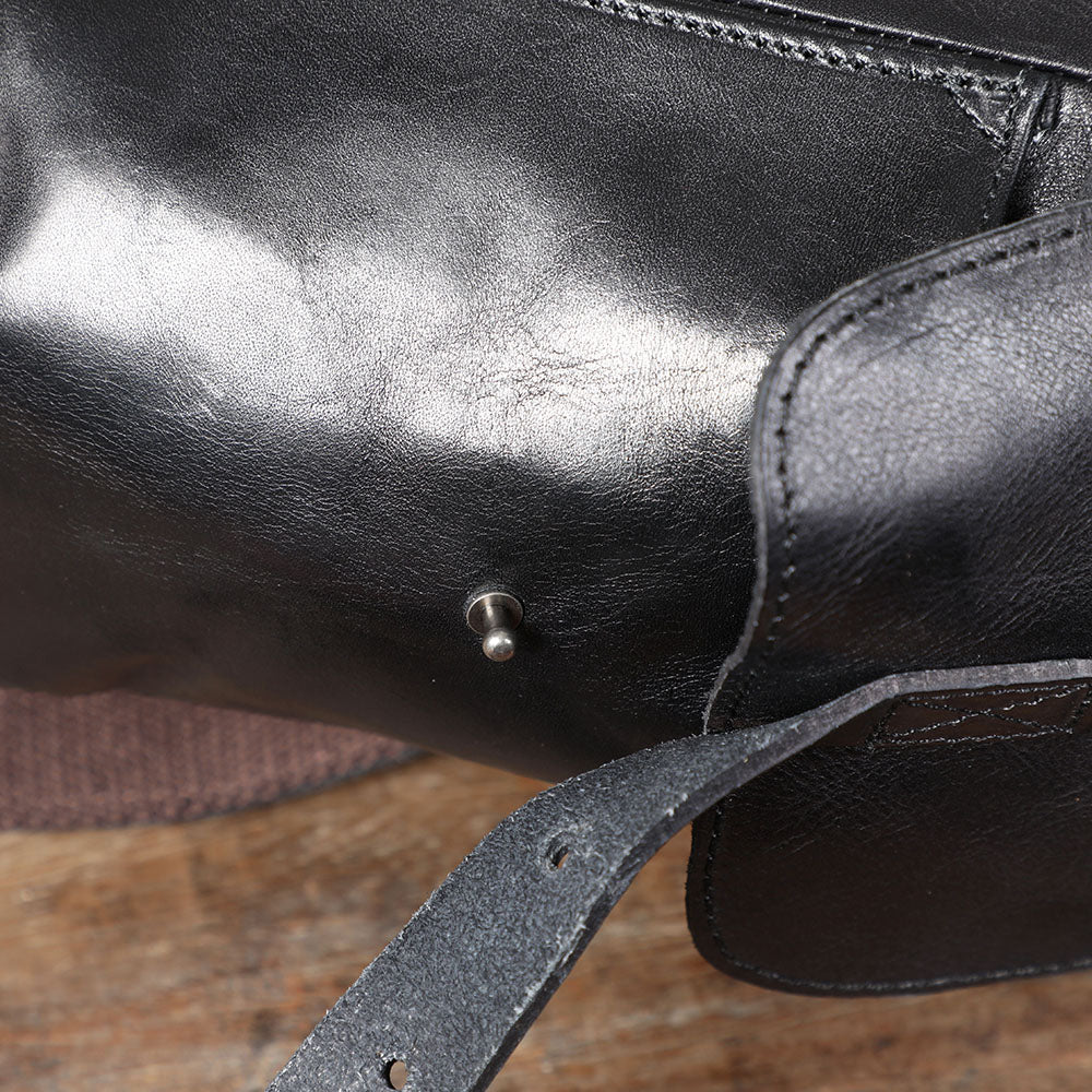 Close-up of a small black leather backpack showing details of the material and hardware.