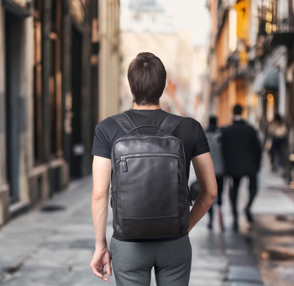 Person wearing a black leather laptop backpack in a city street setting, showcasing style and functionality.