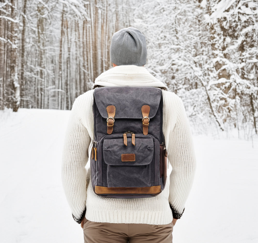 Waterproof canvas camera backpack on a person in snowy forest, showcasing its durability and stylish design.