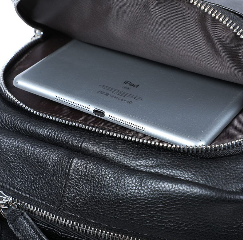 Interior view of a black leather bookbag showing an iPad stored in a padded compartment.