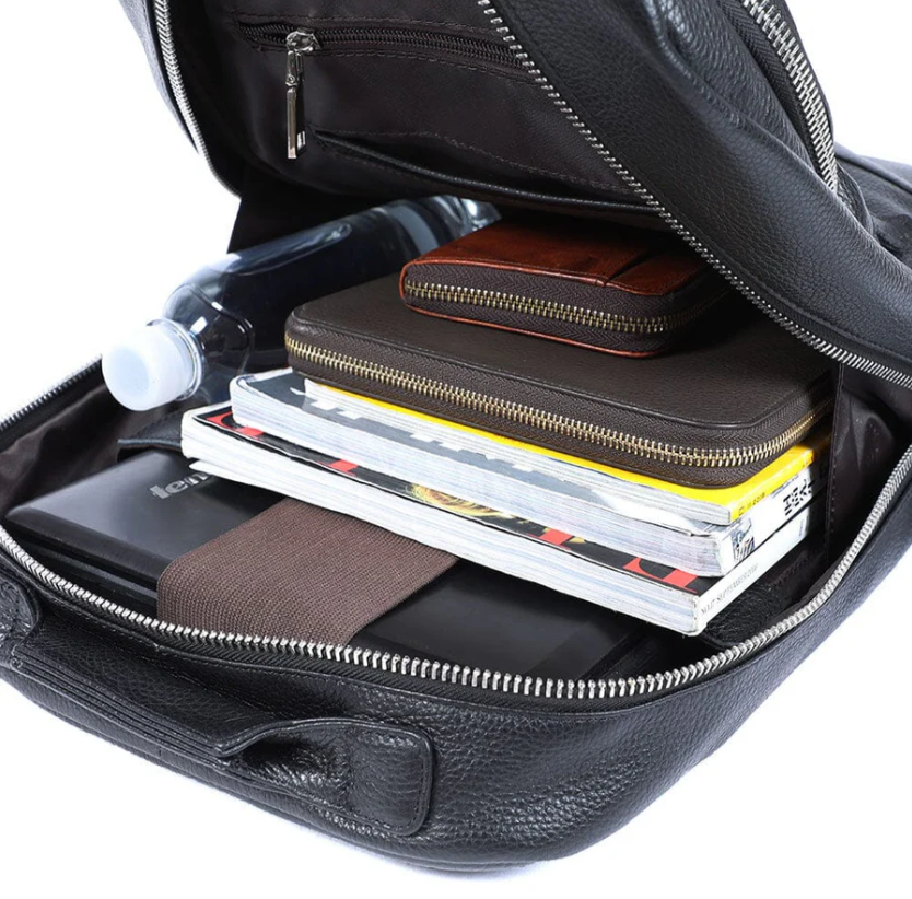Interior view of Black Leather Bookbag with notebooks, water bottle, and brown wallets organized inside.