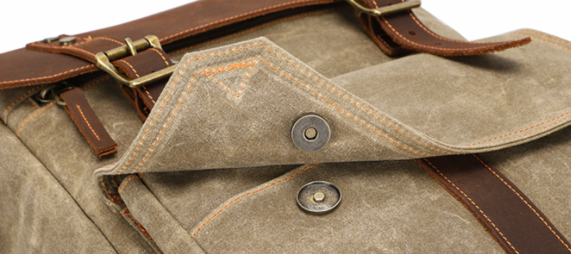 Close-up of a stylish camera backpack with a brown leather trim and detailed stitching, perfect for outdoor adventures.