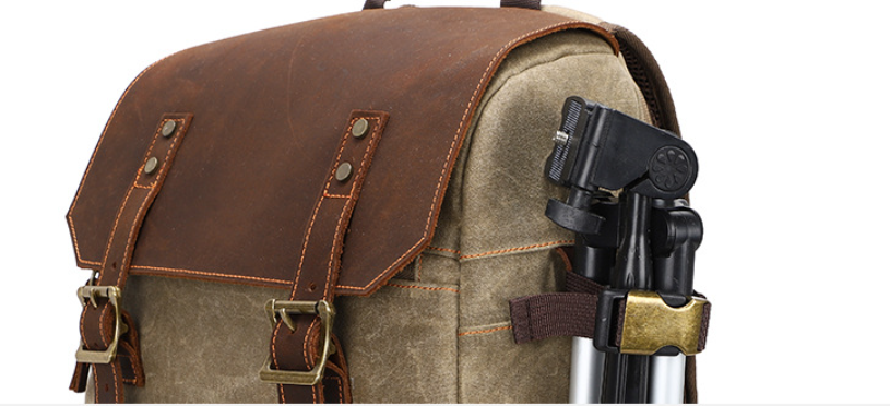 Stylish camera backpack in olive green canvas with brown leather accents and a tripod holder.
