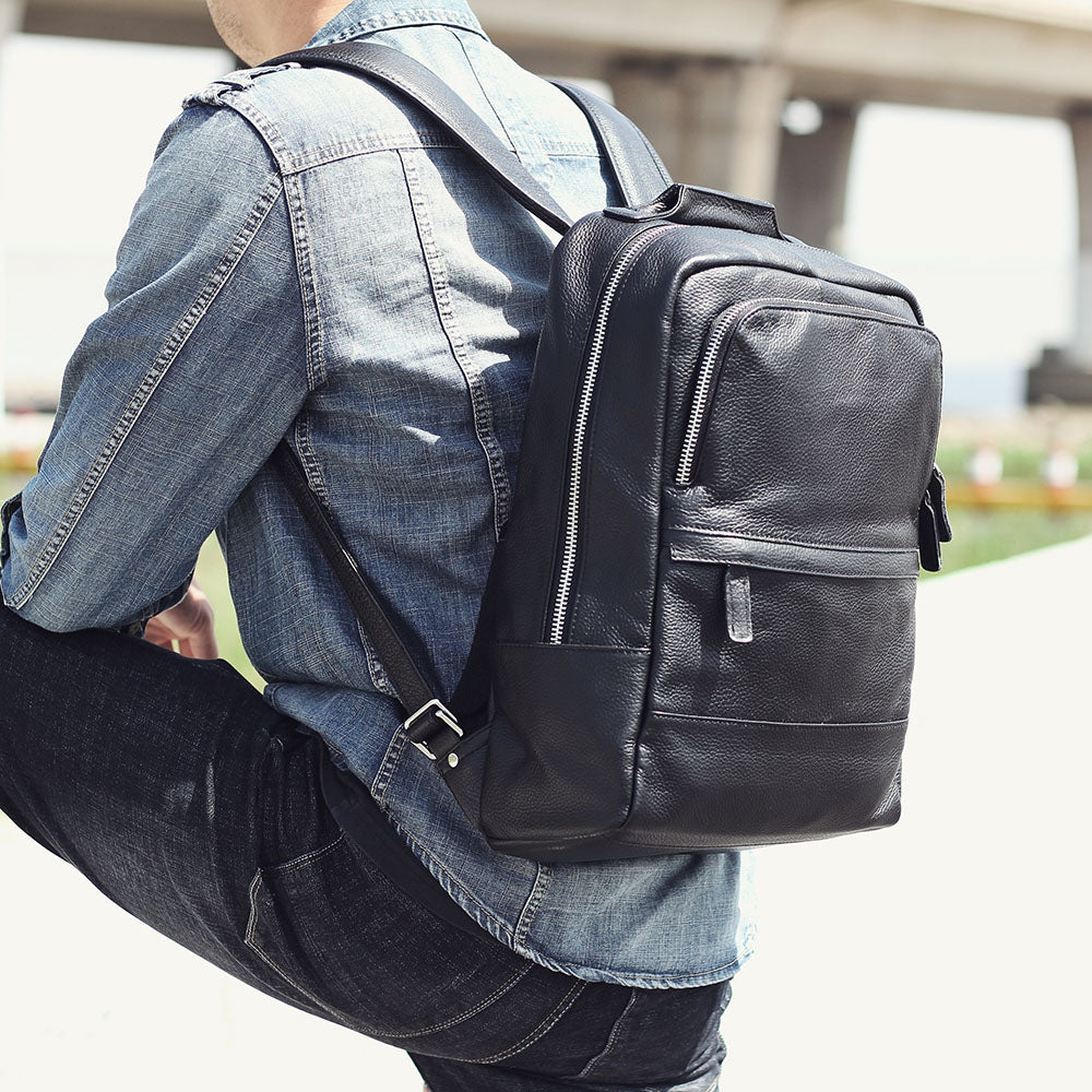 Stylish black leather bookbag worn on the back of a person in casual attire, perfect for daily use.