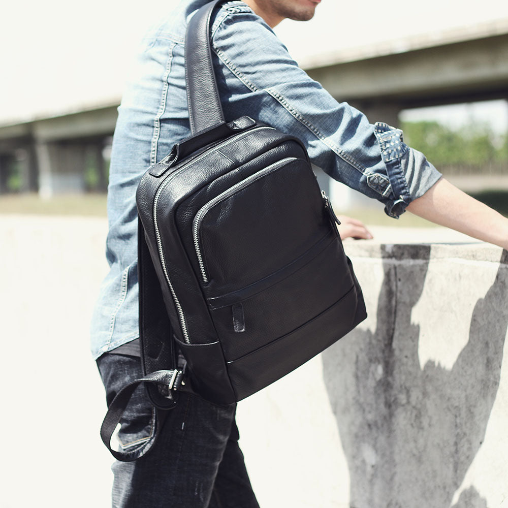 Stylish black leather bookbag worn crossbody by a man in casual attire, perfect for modern travel and daily use.
