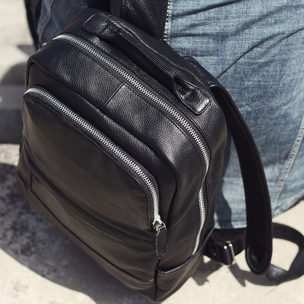 Black leather bookbag from Death Valley, featuring multiple zippers and a stylish design.