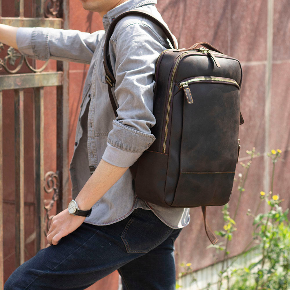 Stylish leather laptop rucksack, Loch Ness model, worn by a man in casual attire against a textured background.