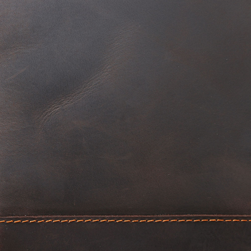 Close-up of dark brown leather with orange stitching, showcasing the rich texture of the Leather Laptop Rucksack.