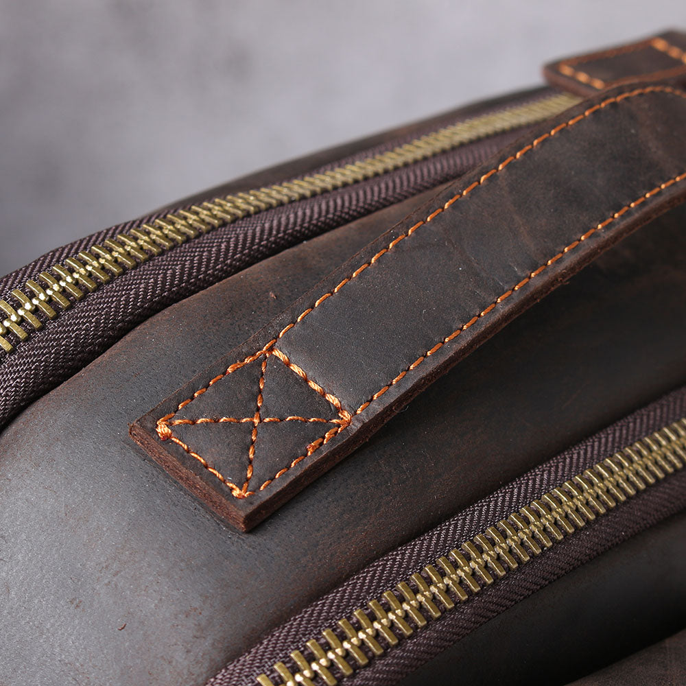 Close-up of leather laptop rucksack handle and zipper detailing, showcasing premium craftsmanship and stylish design.