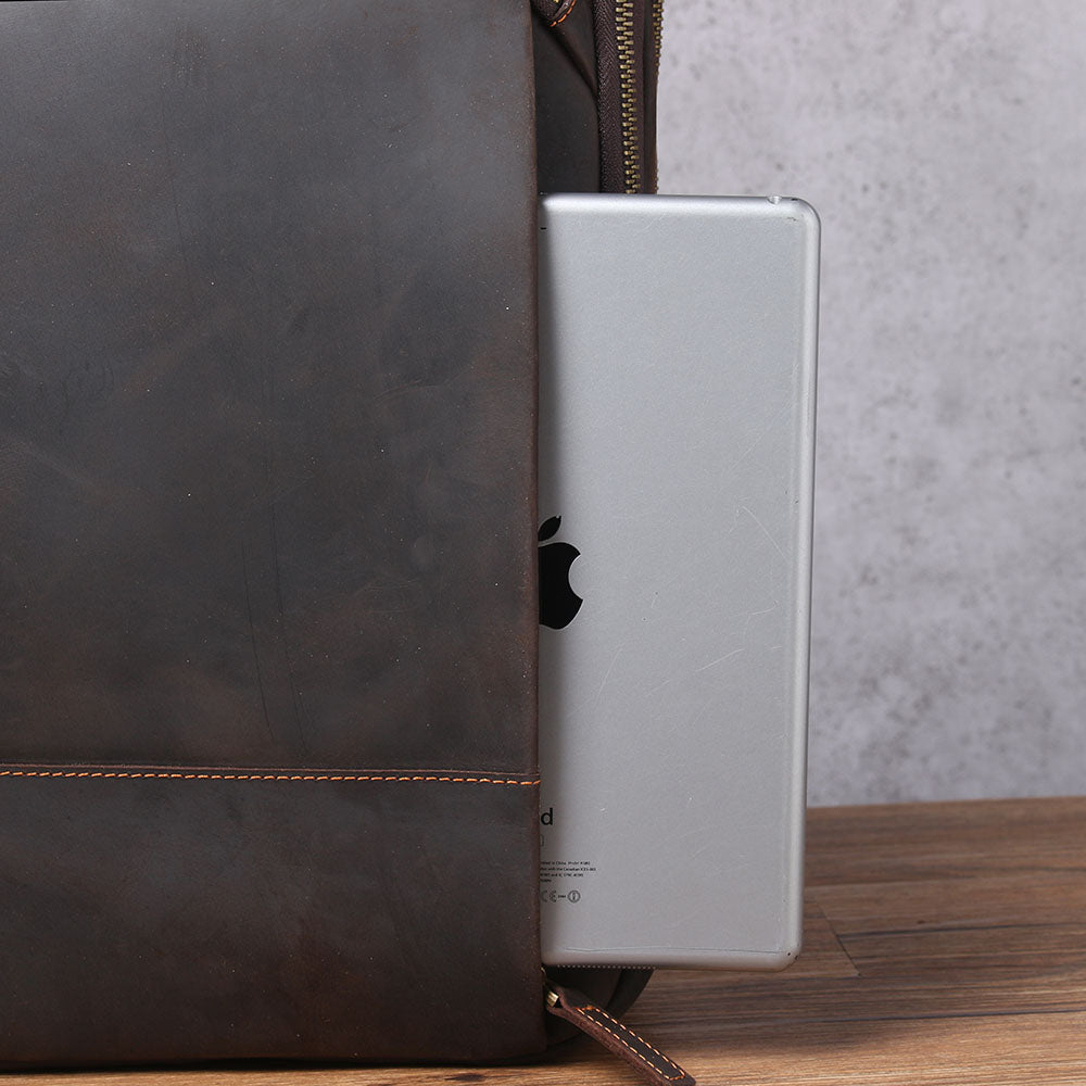 Leather laptop rucksack with a silver laptop partially visible, showcasing spacious interior and modern design.