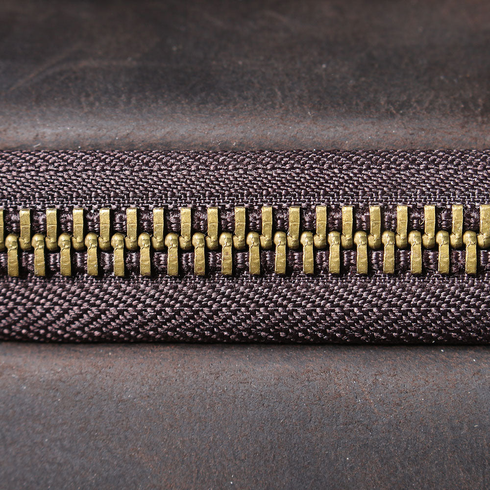 Close-up of a durable bronze zipper on a leather laptop rucksack, showcasing quality craftsmanship.