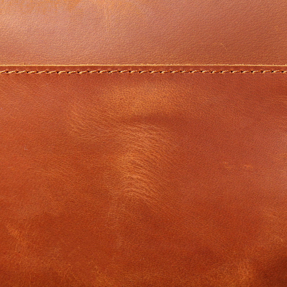 Close-up of premium leather texture featuring rich brown color and stitching details for the Loch Ness rucksack.