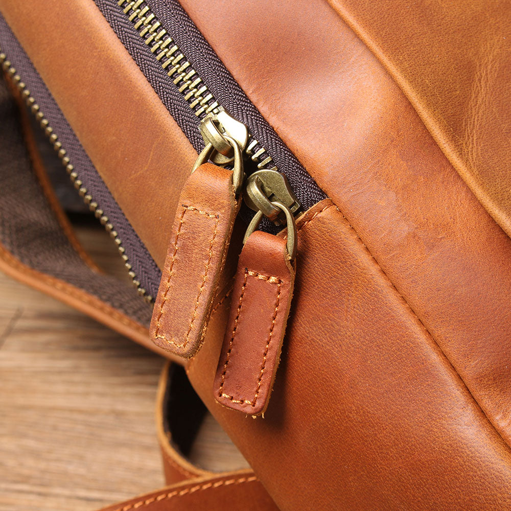 Close-up of leather laptop rucksack zipper showing durable brass hardware and quality stitching details.