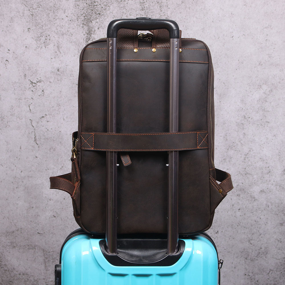 Leather Laptop Rucksack on top of a suitcase, showcasing its sleek design and functionality for travel.