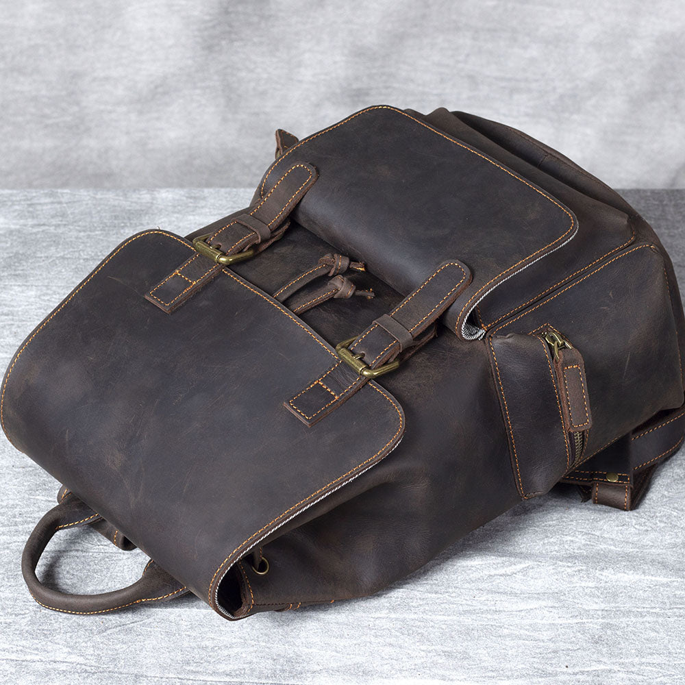 Black leather drawstring backpack with two front buckles and pockets, perfect for stylish everyday use.