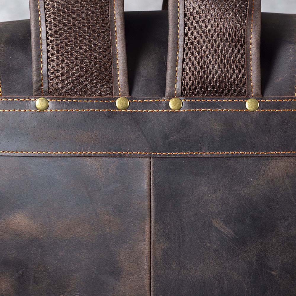 Close-up of brown leather drawstring backpack showing textured straps and stitching details.