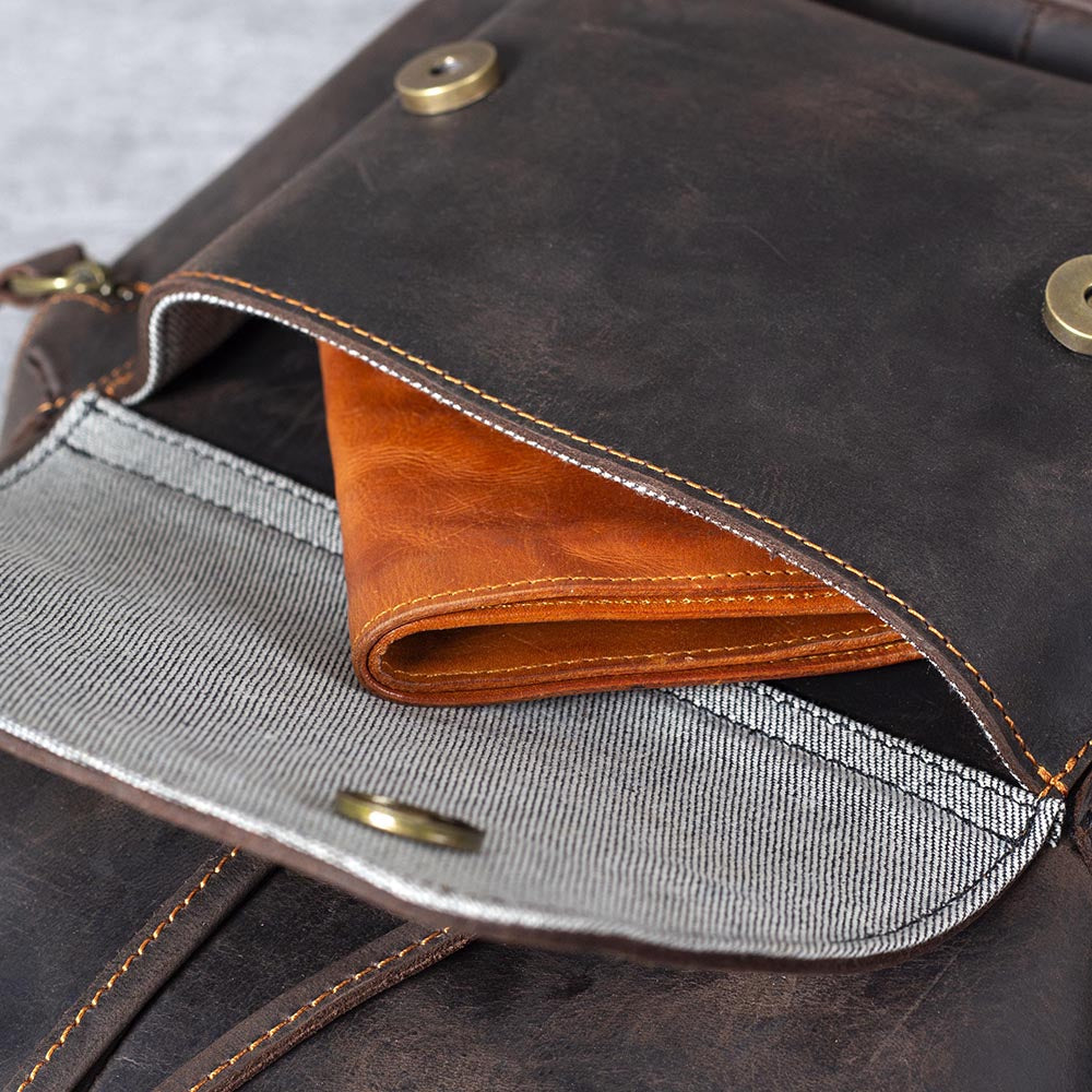 Interior view of black leather drawstring backpack showcasing a brown wallet in the pocket.