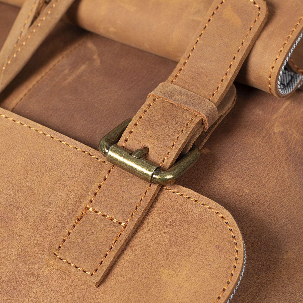 Close-up of a leather drawstring backpack strap and buckle, showcasing premium craftsmanship.