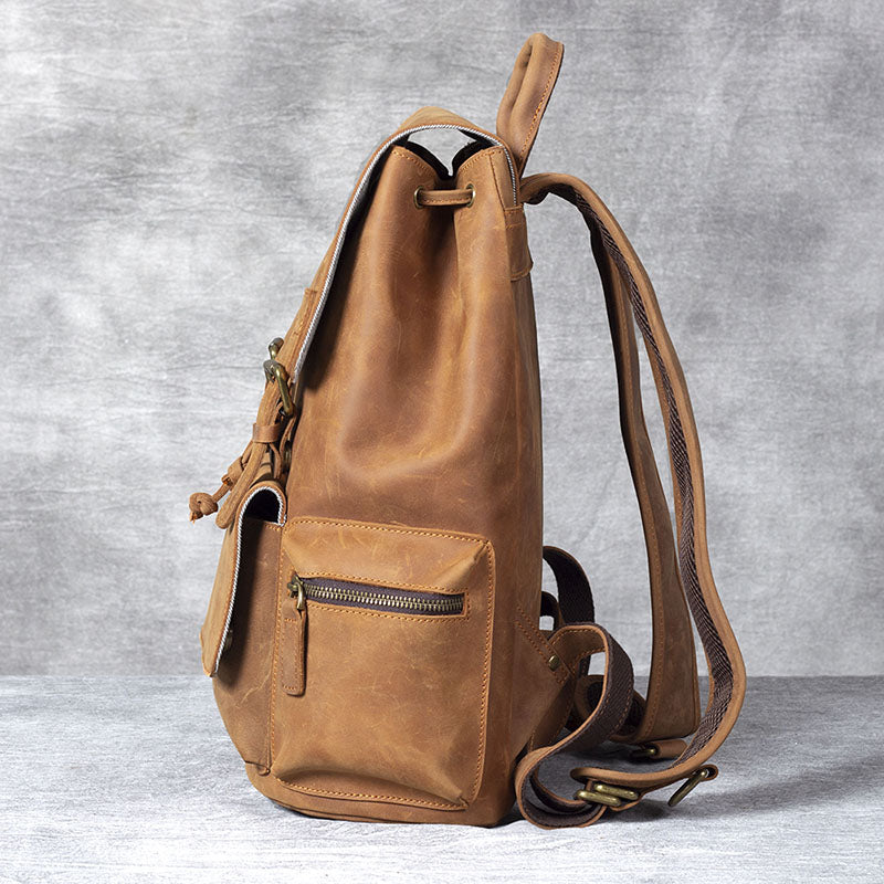 Stylish leather drawstring backpack in a warm tan color, featuring a side pocket and adjustable straps.