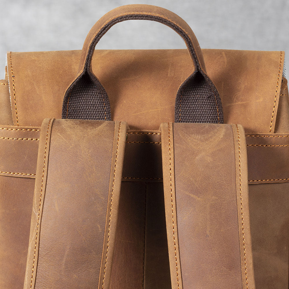 Close-up of a leather drawstring backpack showcasing its sturdy straps and top handle.