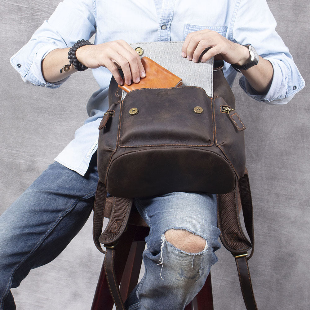 Man opening leather drawstring backpack, showcasing organizer pocket for phone and accessories.