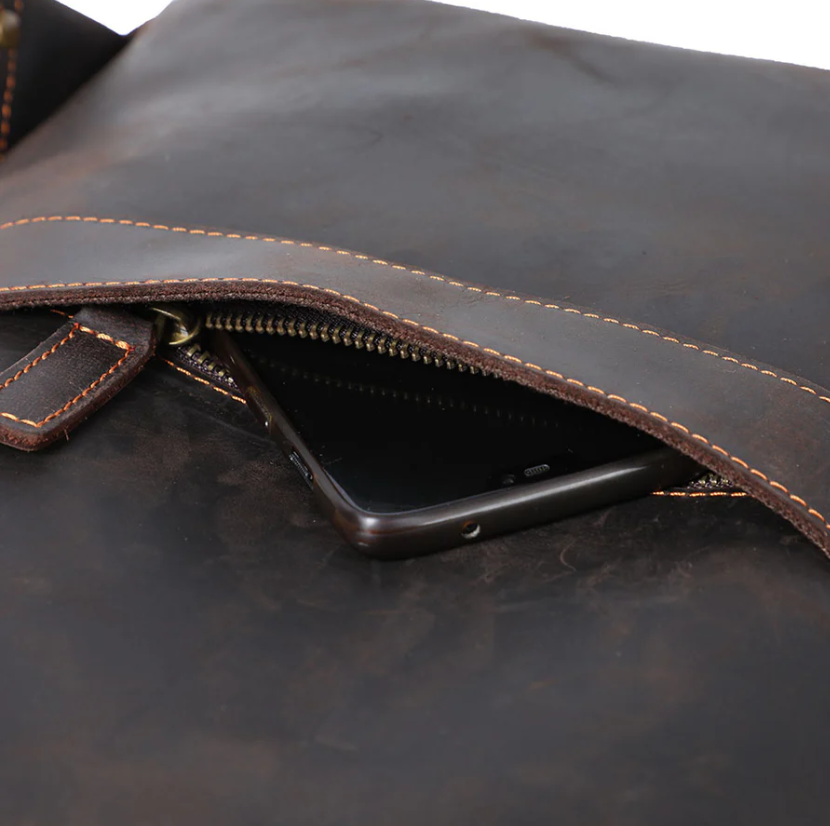 Close-up of the leather laptop rucksack zip pocket showing a smartphone inside it.