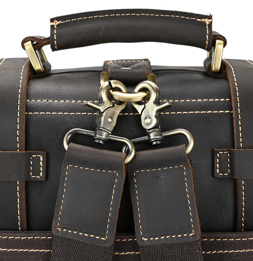 Close-up of a leather rucksack handle and straps with metal clasps, showcasing craftsmanship and quality.
