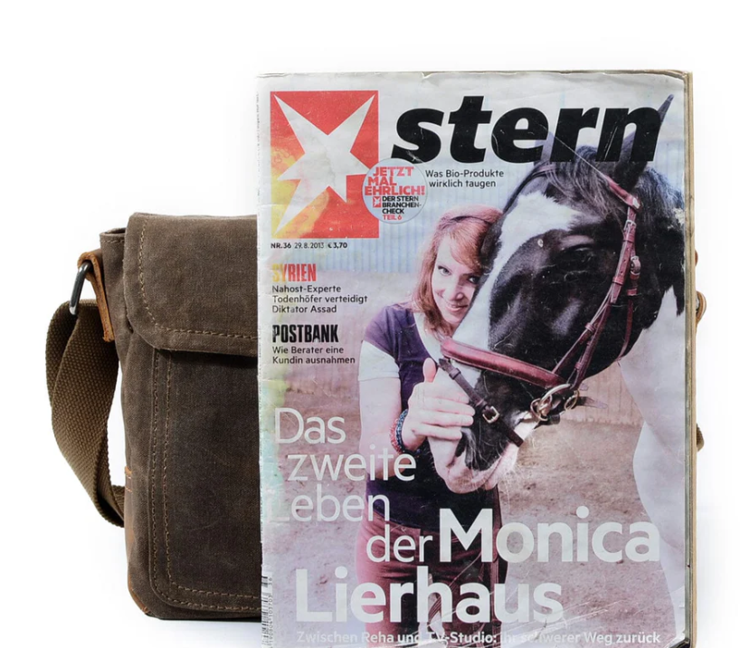Small canvas messenger bag next to a magazine on a white background, showcasing a casual and stylish accessory.