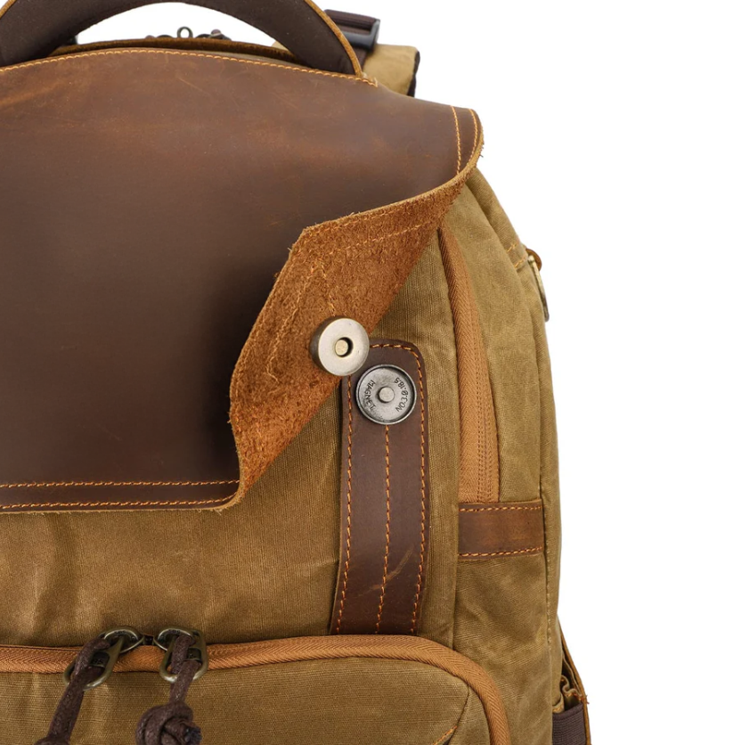 Vintage camera backpack detail featuring leather flap, metal button, and durable fabric for outdoor adventures.