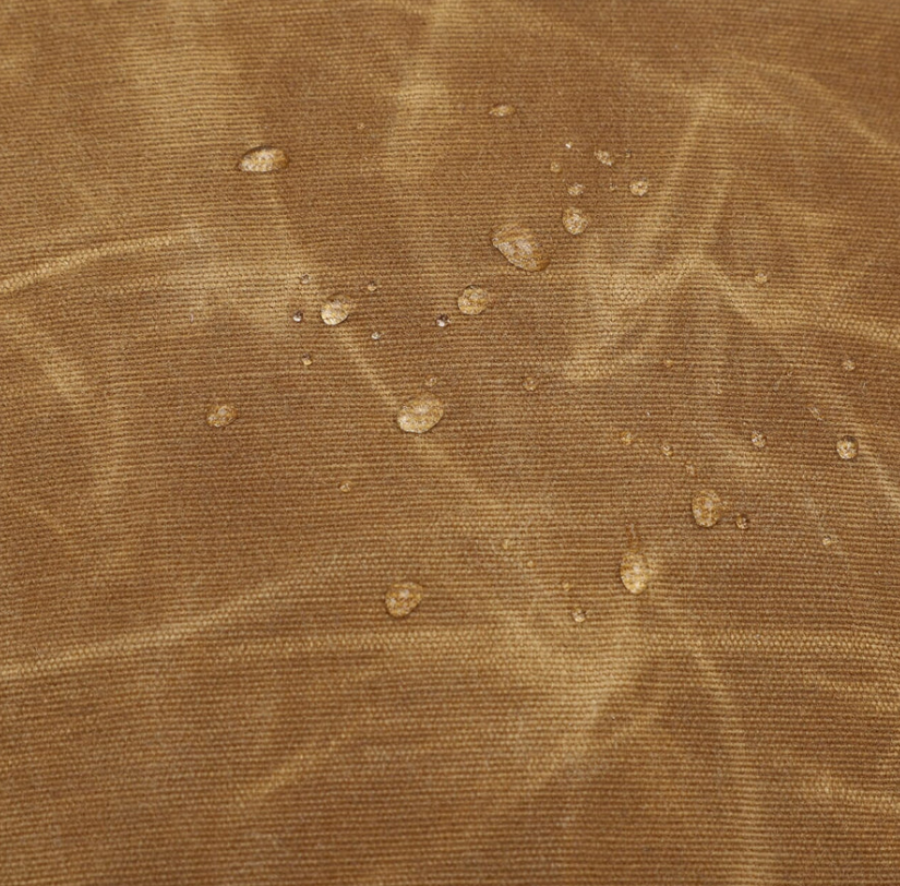 Water-resistant fabric close-up showing droplets on a vintage camera backpack in Sierra Nevada design.