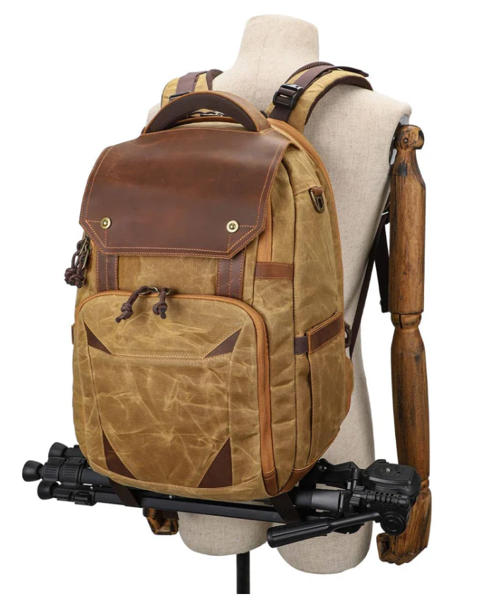 Vintage camera backpack with leather accents, designed for photographers, displayed on a mannequin with a tripod.