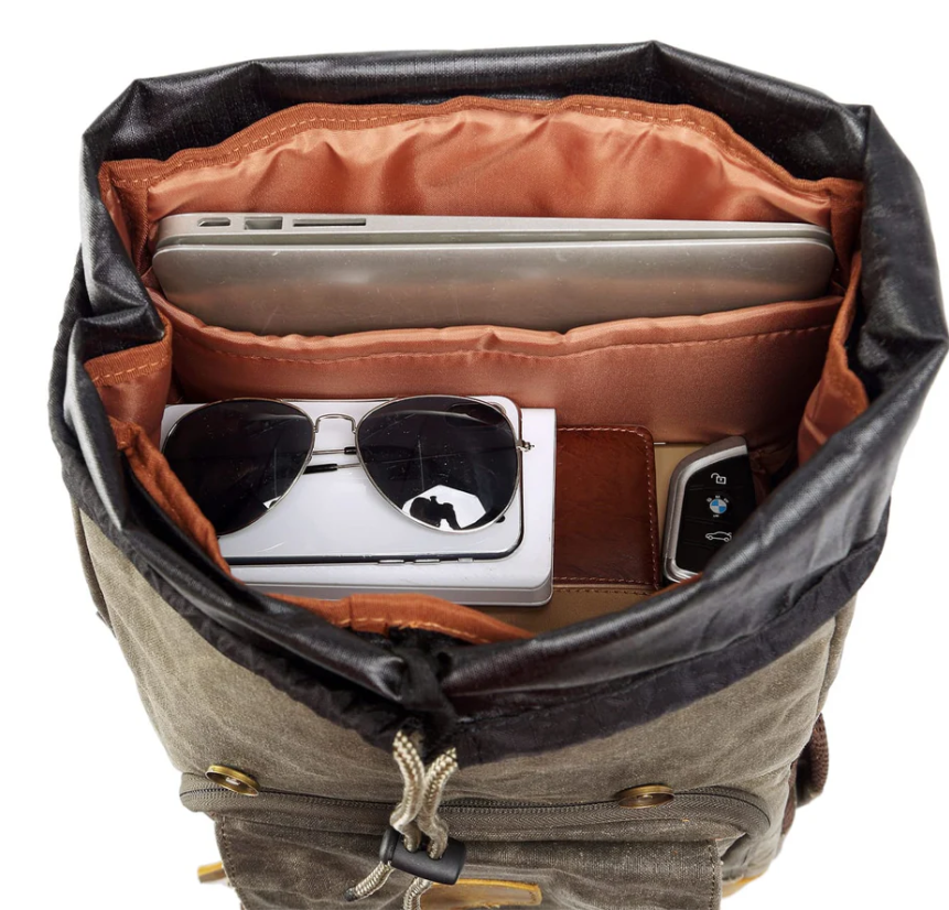 Interior view of waterproof canvas camera backpack featuring laptop, sunglasses, and accessories for photographers.