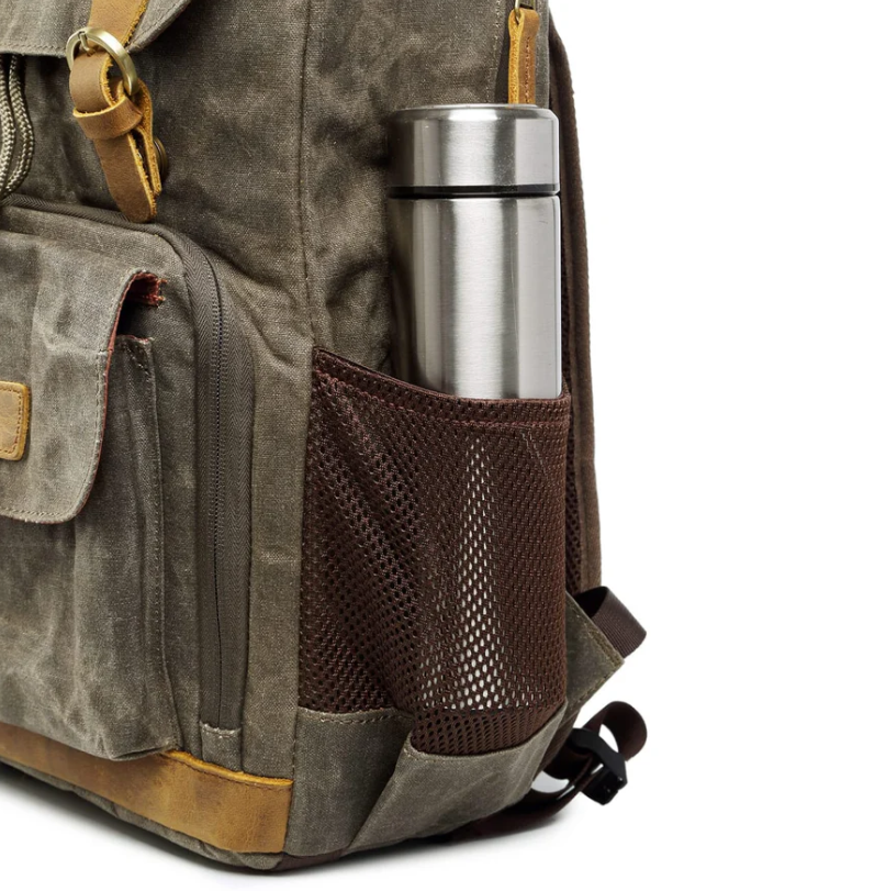 Side view of a waterproof canvas camera backpack featuring a slim stainless steel thermos in a mesh pocket.