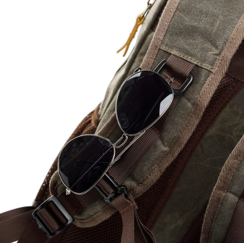 Close-up of waterproof canvas camera backpack featuring stylish sunglasses attached.