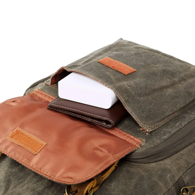 Close-up of the waterproof canvas camera backpack's top pocket with cards and a small device.