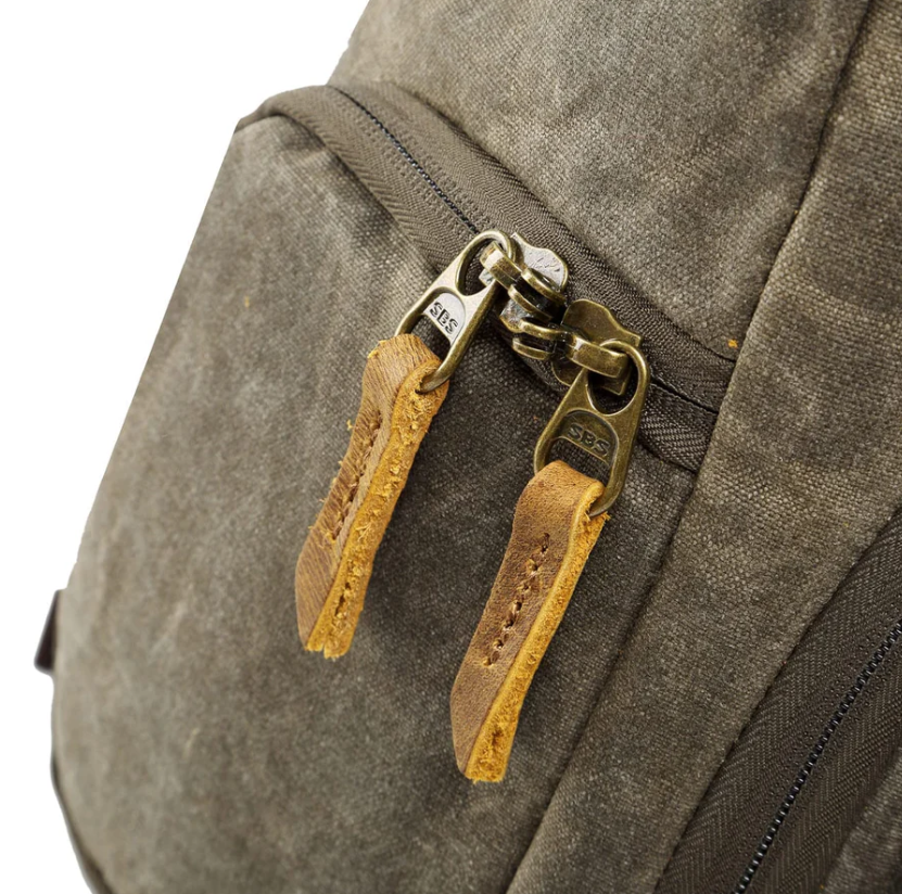 Close-up of waterproof canvas camera backpack zippers with leather pulls, perfect for outdoor photography in Antarctica.